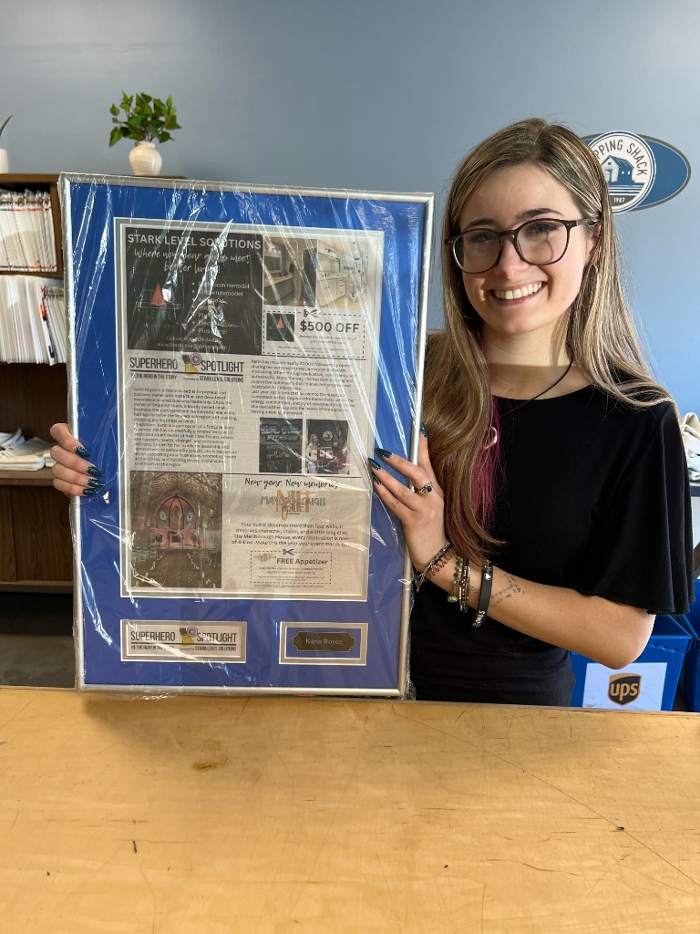 A featured hero's daughter holding a framed SuperHero Spotlight memory plaque